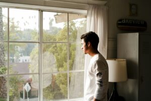 La soledad que no se nota: por qué uno de cada cinco chilenos se siente excluido Persona mirando por una ventana en un departamento minimalista, luz natural tenue