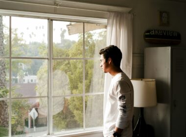 Persona mirando por una ventana en un departamento minimalista, luz natural tenue