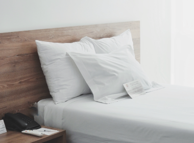 Habitación de hotel minimalista con cama blanca y luz natural suave