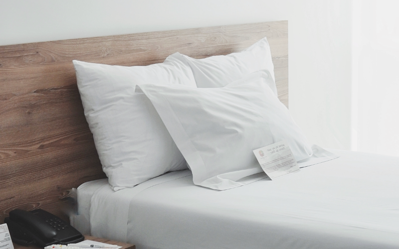Habitación de hotel minimalista con cama blanca y luz natural suave