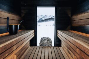 El calor que nos vuelve a juntar: por qué la sauna dejó de ser un lujo solitario Interior de sauna nórdica con luz cálida natural, ambiente minimalista y textura de madera