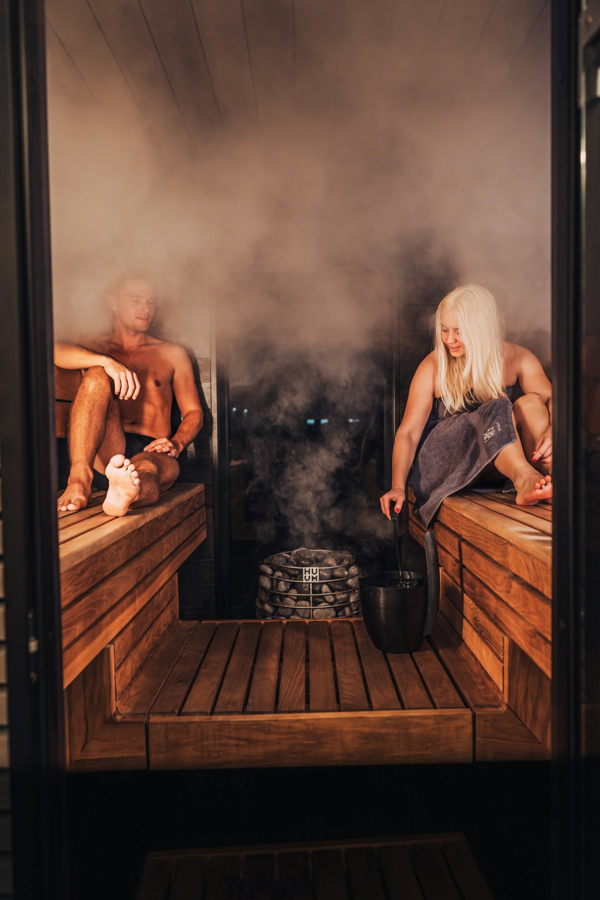 Dos personas conversando en un lounge de sauna con iluminación suave