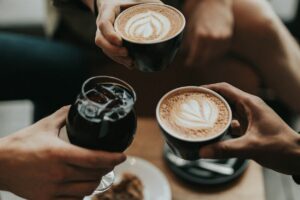 Sober curious: por qué socializar sin alcohol se volvió la nueva conexión Cuatro amigos riendo y celebrando con café, ambiente social diurno y alegre