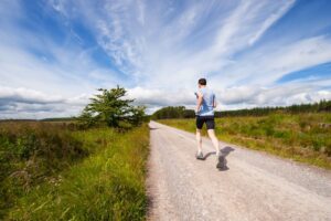 El entrenamiento lento gana: qué dice la ciencia sobre la zona 2 Hombre corriendo a un ritmo calmado en una carretera de asfalto, luz natural de día