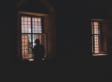 Persona sentada junto a una ventana en actitud reflexiva, luz suave de interior