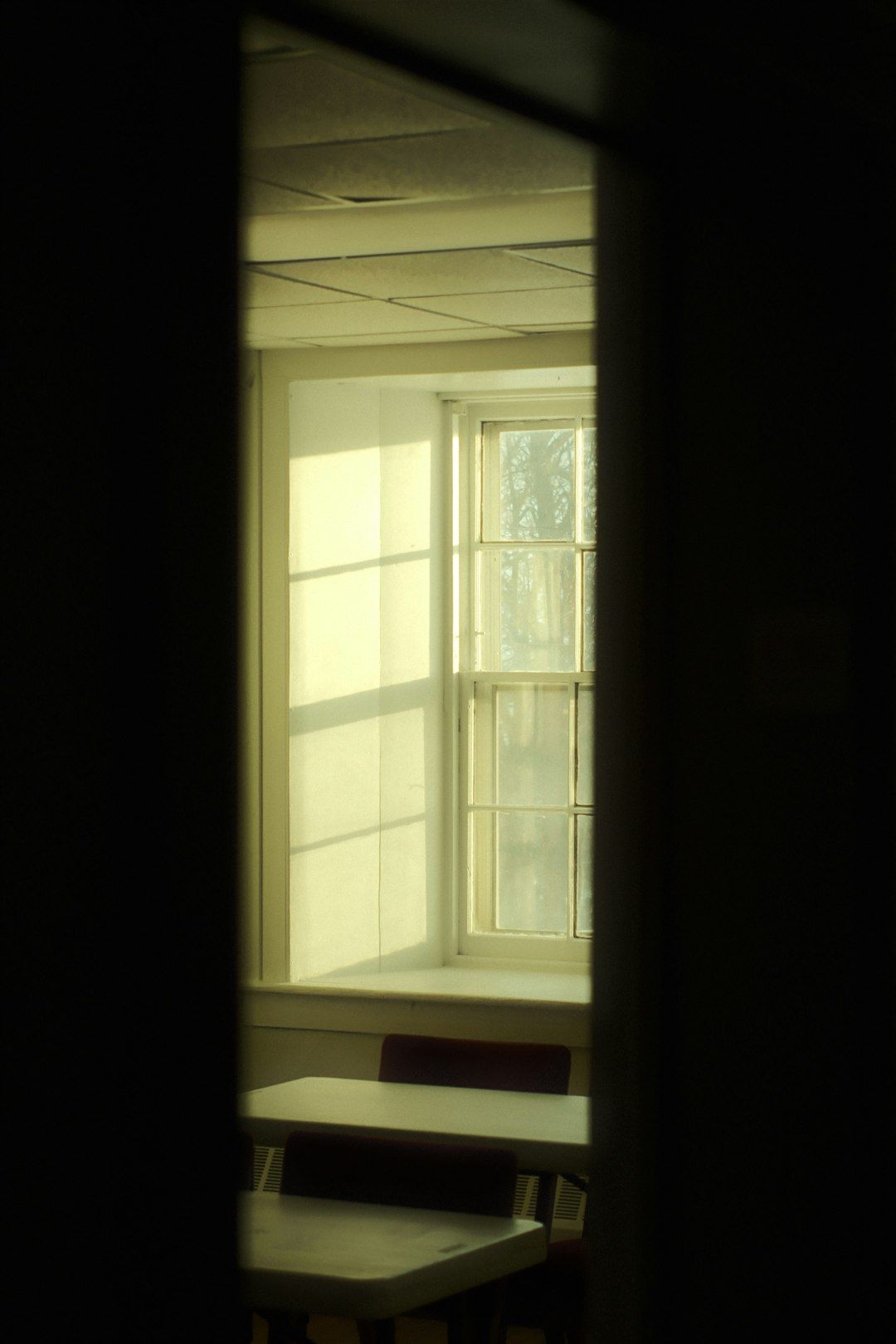 Ventana en nicho profundo con luz solar dramática entrando en un espacio silencioso