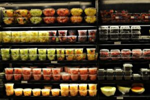 Cómo los medicamentos para bajar de peso están rediseñando el carrito de compras Carrito de supermercado con frutas frescas, yogur y proteínas, composición editorial