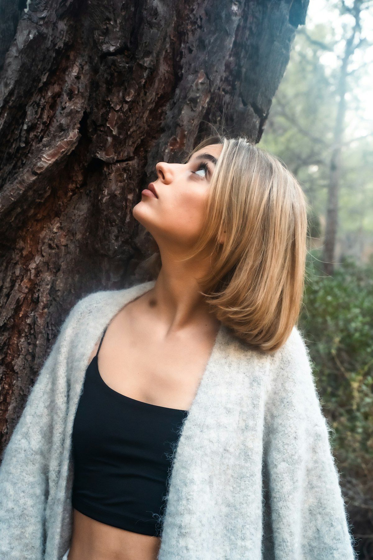Mujer de pie en un sendero natural rodeada de árboles, luz natural