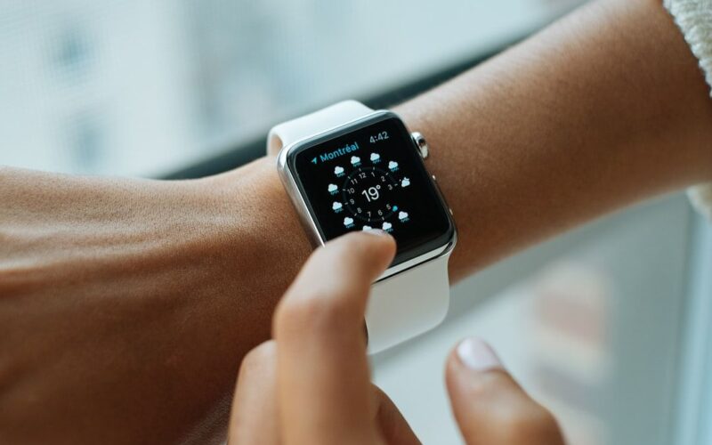 Persona revisando un reloj inteligente en la muñeca durante la mañana, luz natural suave